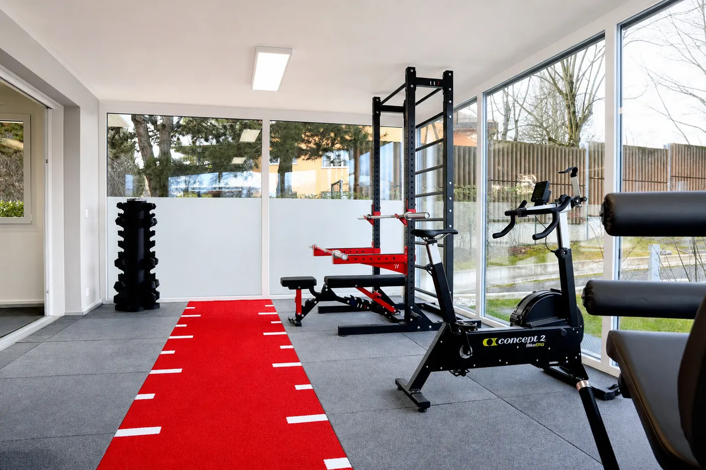 Plateau technique du cabinet de Saint-Sulpice : piste rouge, rack, vélo et baies vitrées sur le jardin